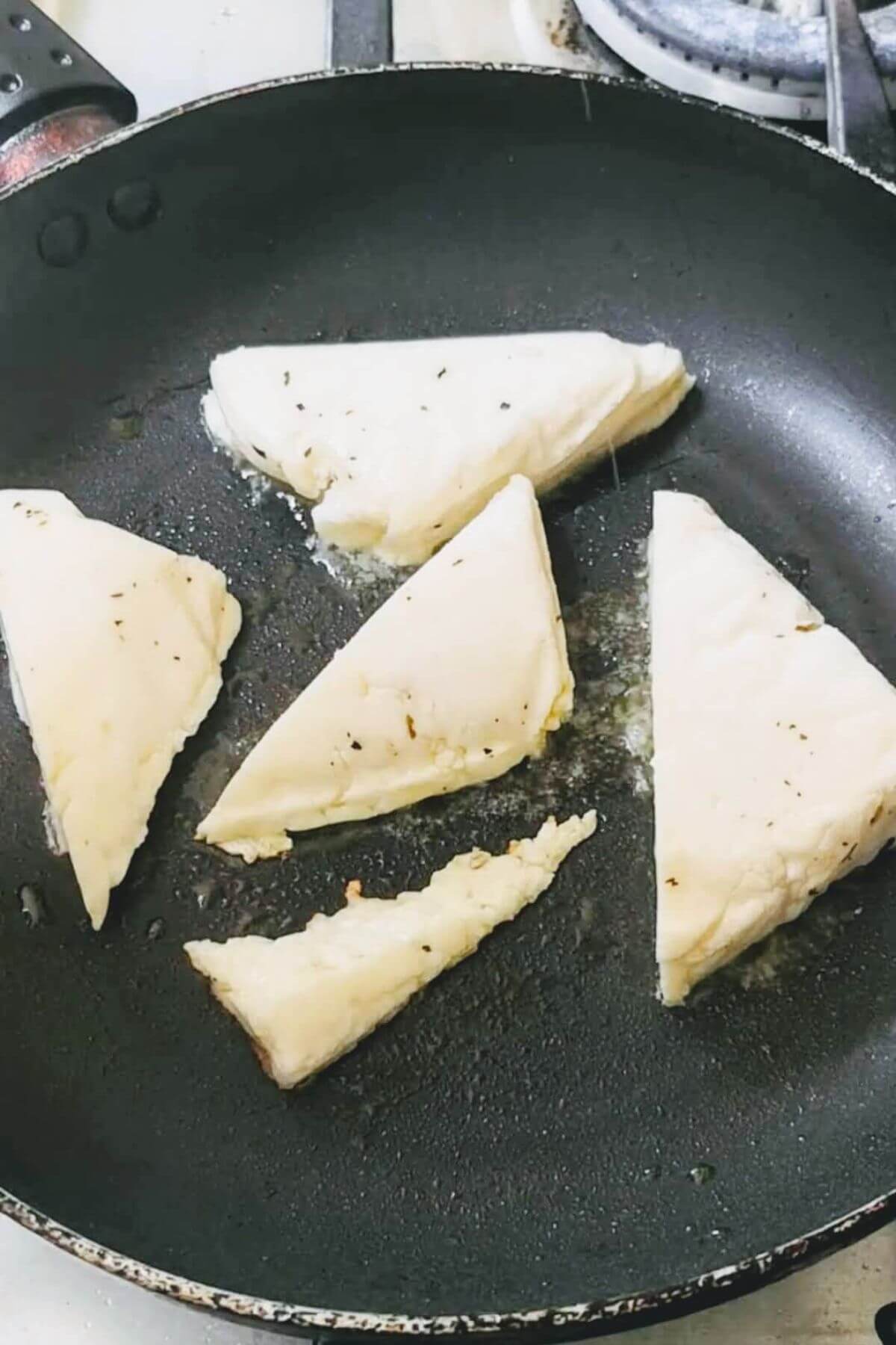Five halloumi triangles cooking in the pan