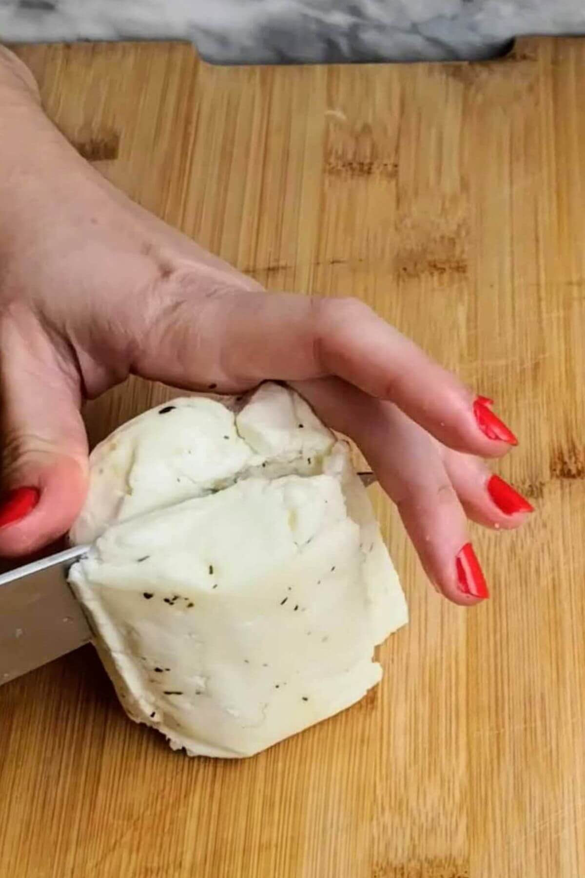 Block of halloumi being chopped in half