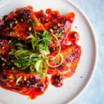 Halloumi triangles glazed with honey and harissa on a plate topped with spring onion and dukkah