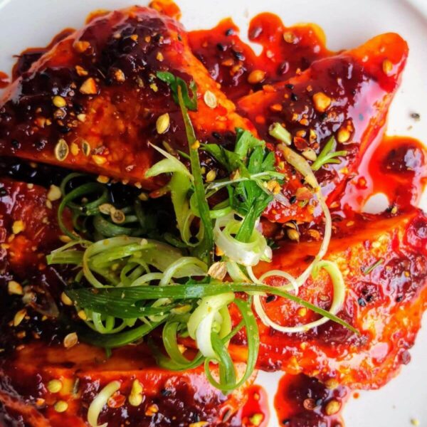 Halloumi triangles glazed with honey and harissa on a plate topped with spring onion and dukkah