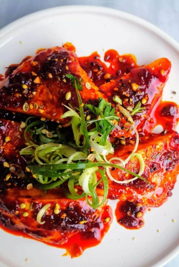 Halloumi triangles glazed with honey and harissa on a plate topped with spring onion and dukkah