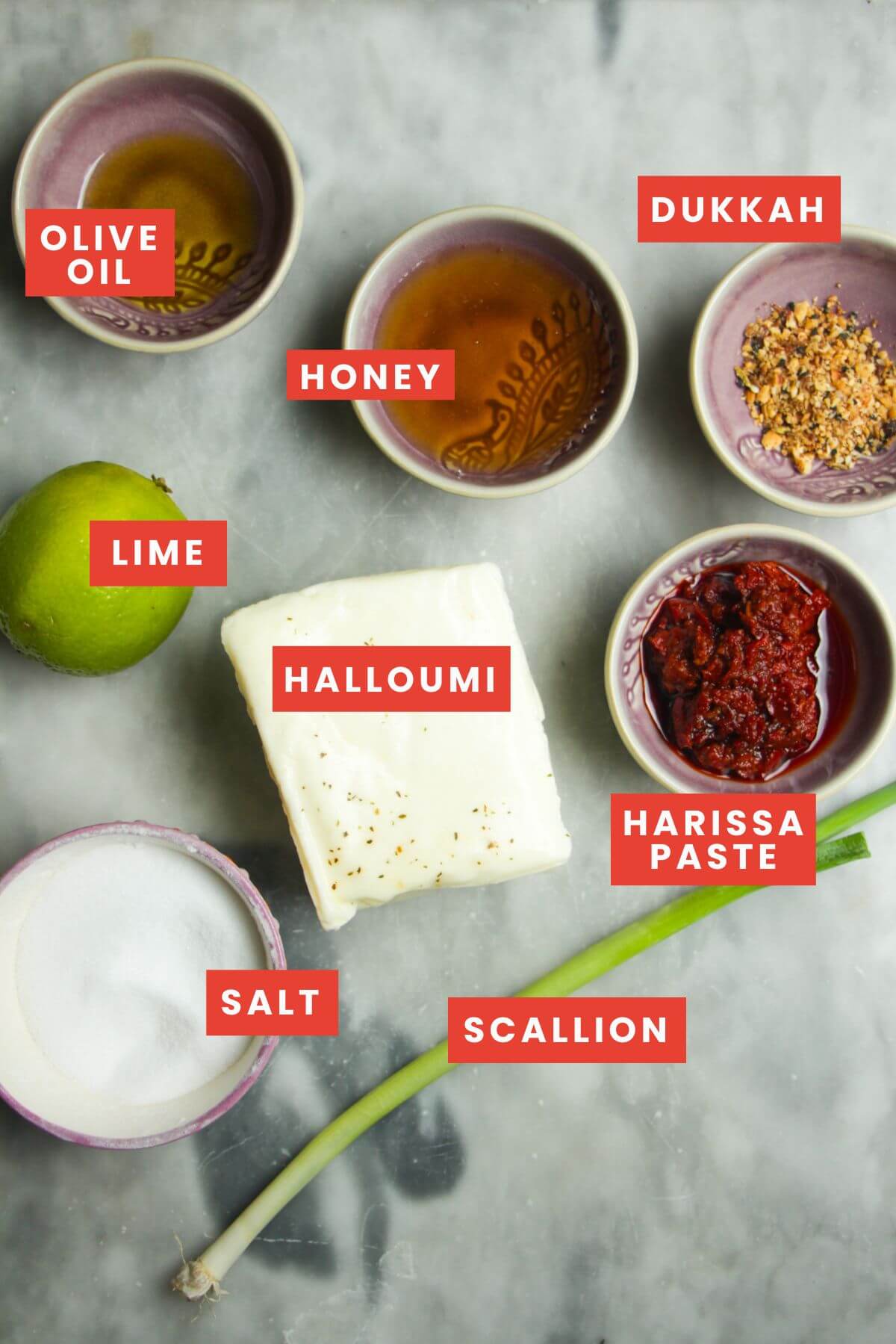Ingredients for honey harissa halloumi laid out on a grey marble background.