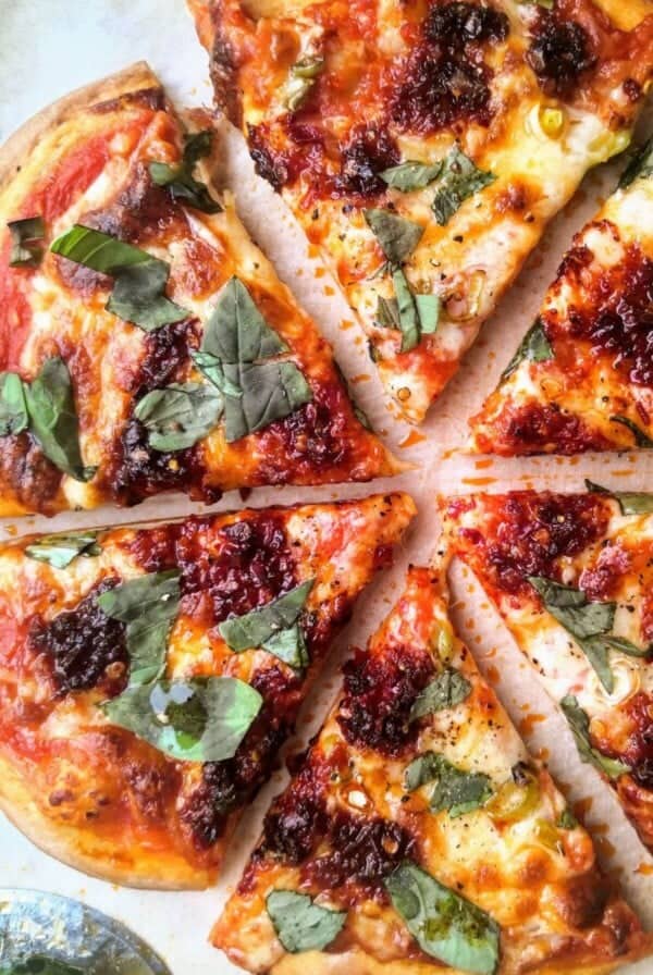 Nduja, spring onion and honey pizza sliced on a board.
