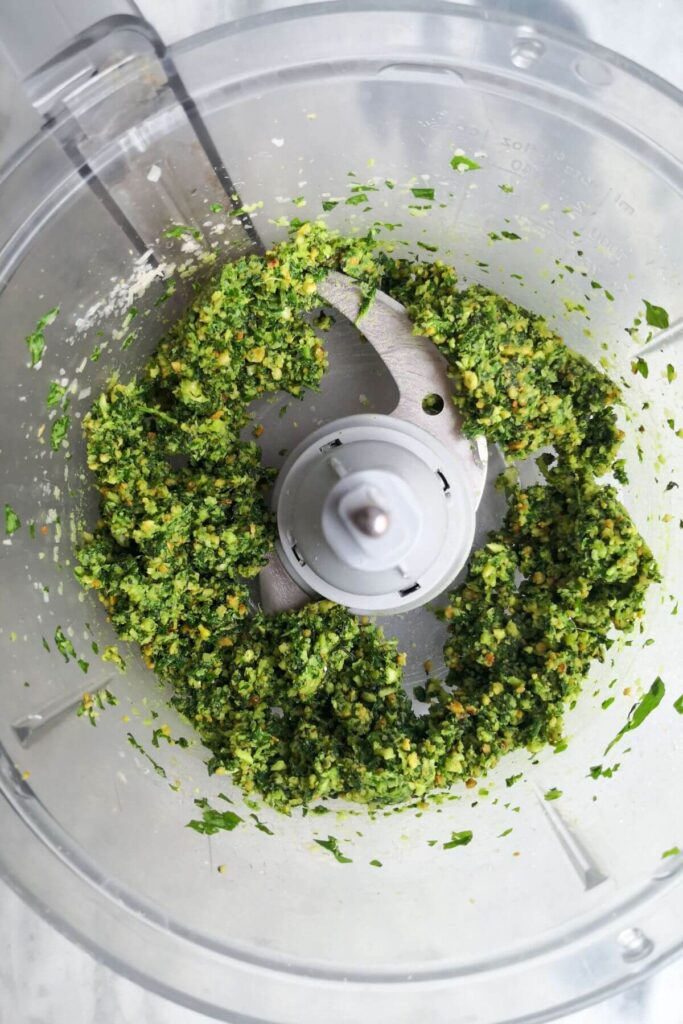 Blitzed basil leaves, garlic, pine nuts and lemon juice in the bowl of a food processor.