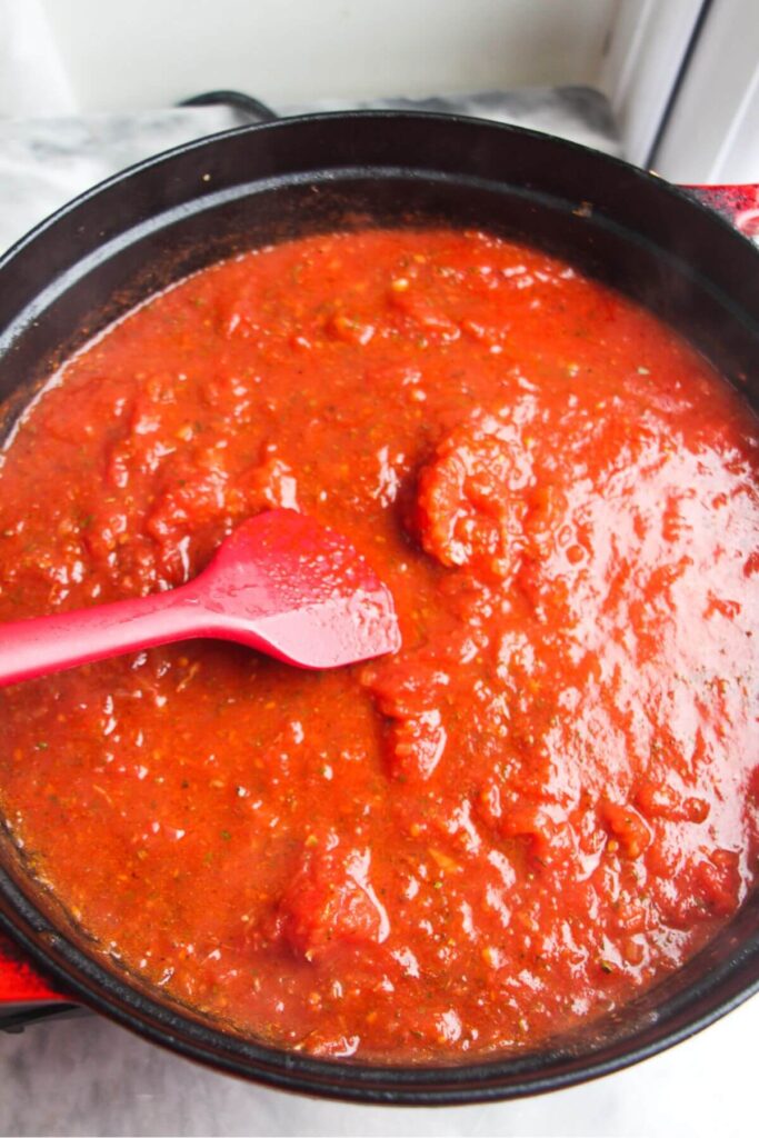 Tomato sauce cooked down in a large black pan.