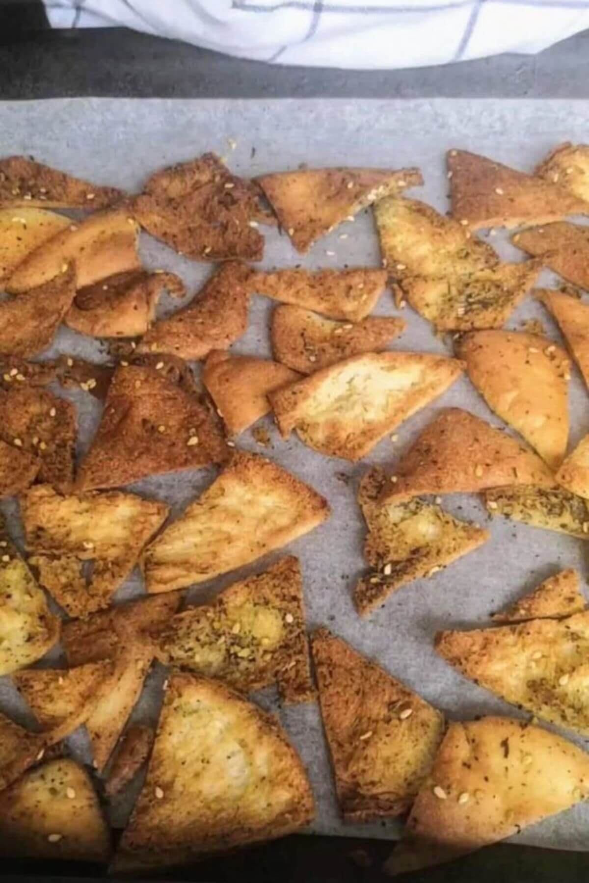 Cooked pita chips on a baking paper lined tray