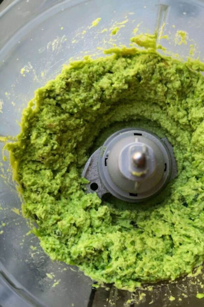 Edamame hummus with avocado blitzed up in the bowl of a food processor.