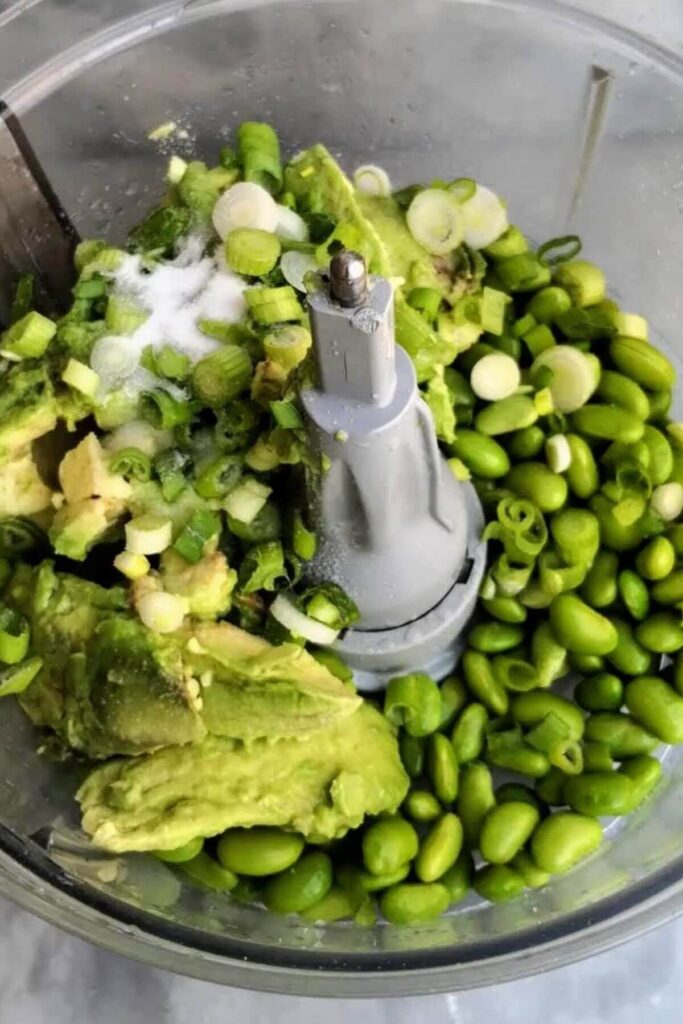 Edamame, avocado, spring onion in the bowl of a food processor.