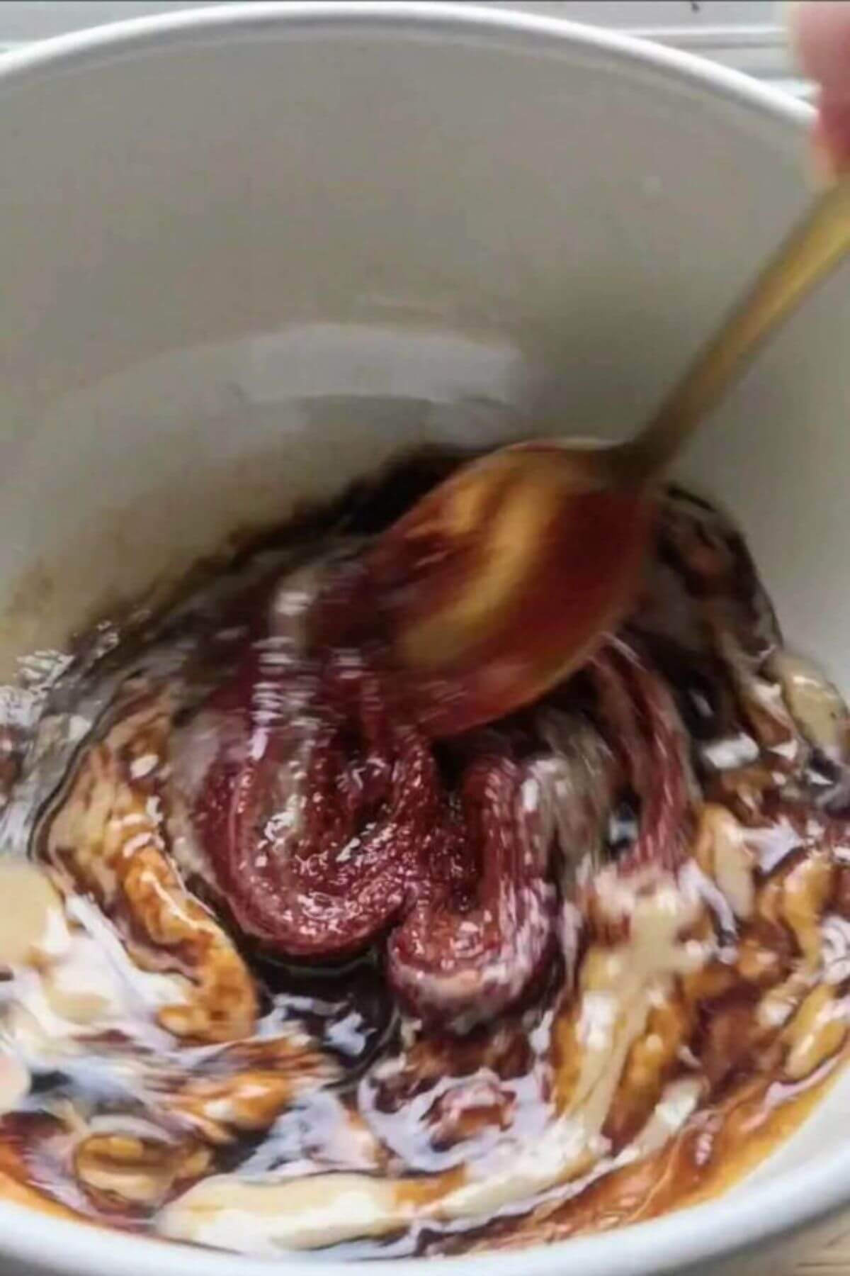 Gochujang, tahini paste being stirred in a small white bowl.