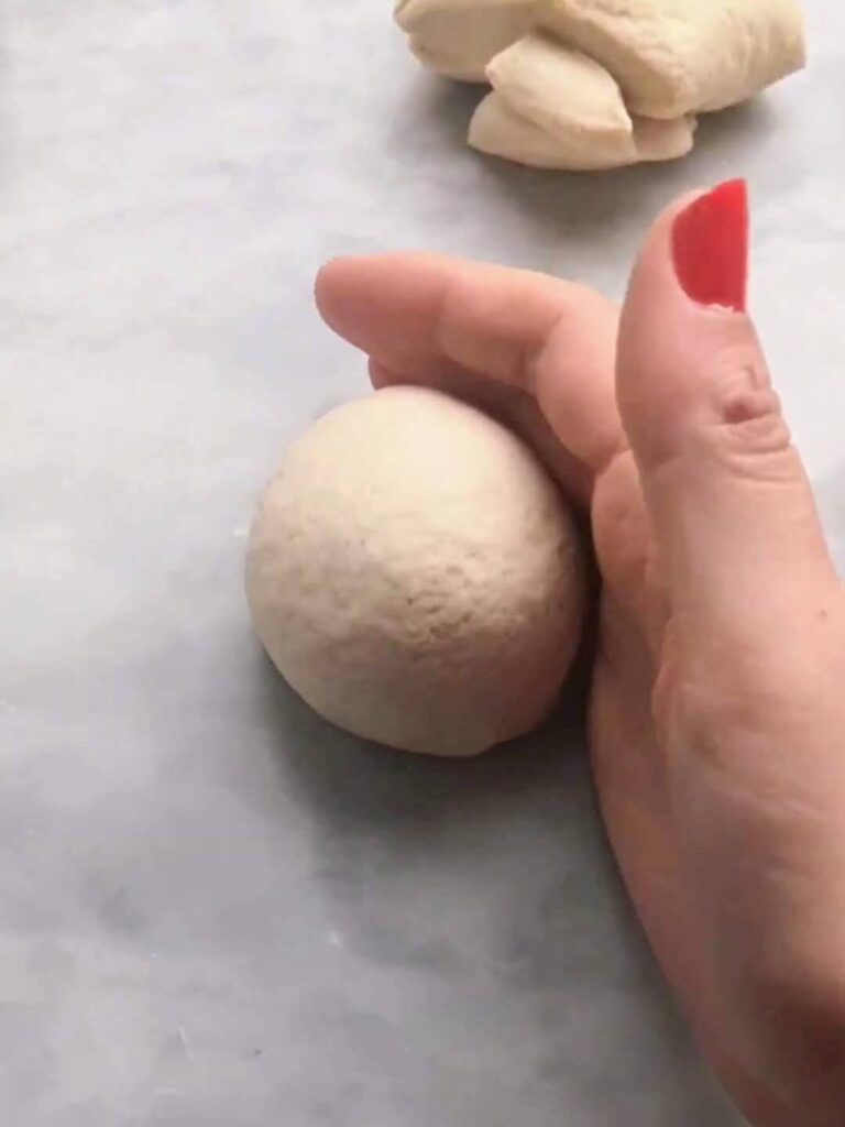 A hand forming the easy soft flatbread dough into small balls.