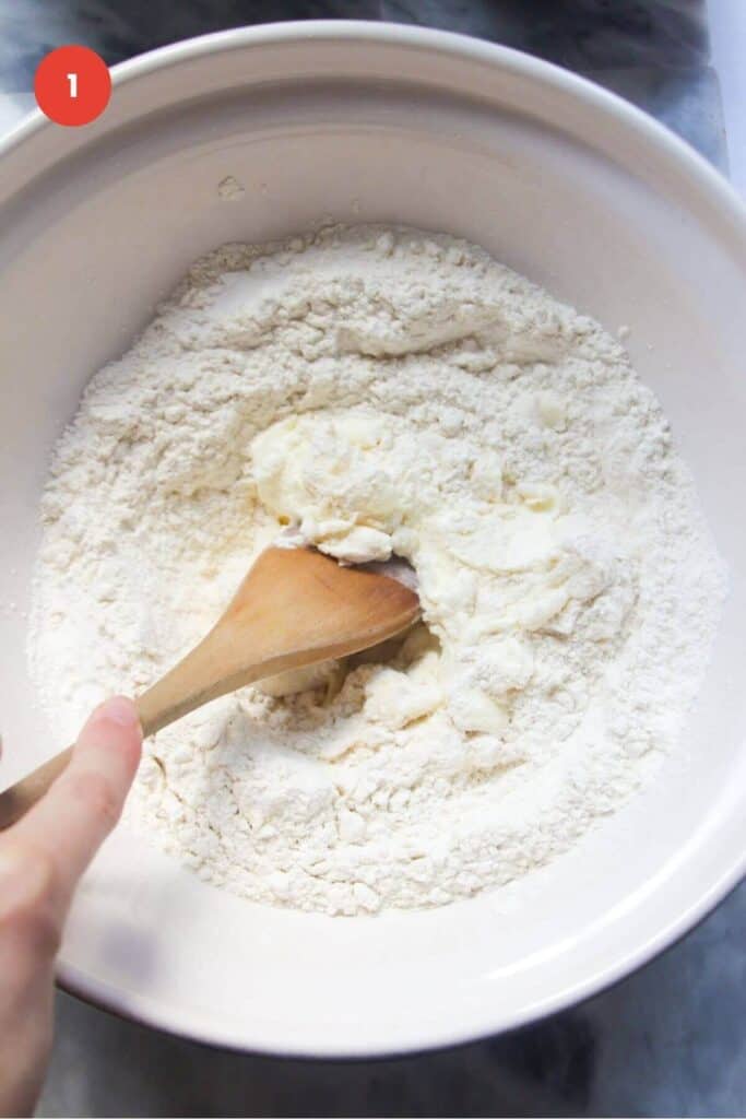 Mixing flour and yogurt in mixing bowl with spatula.