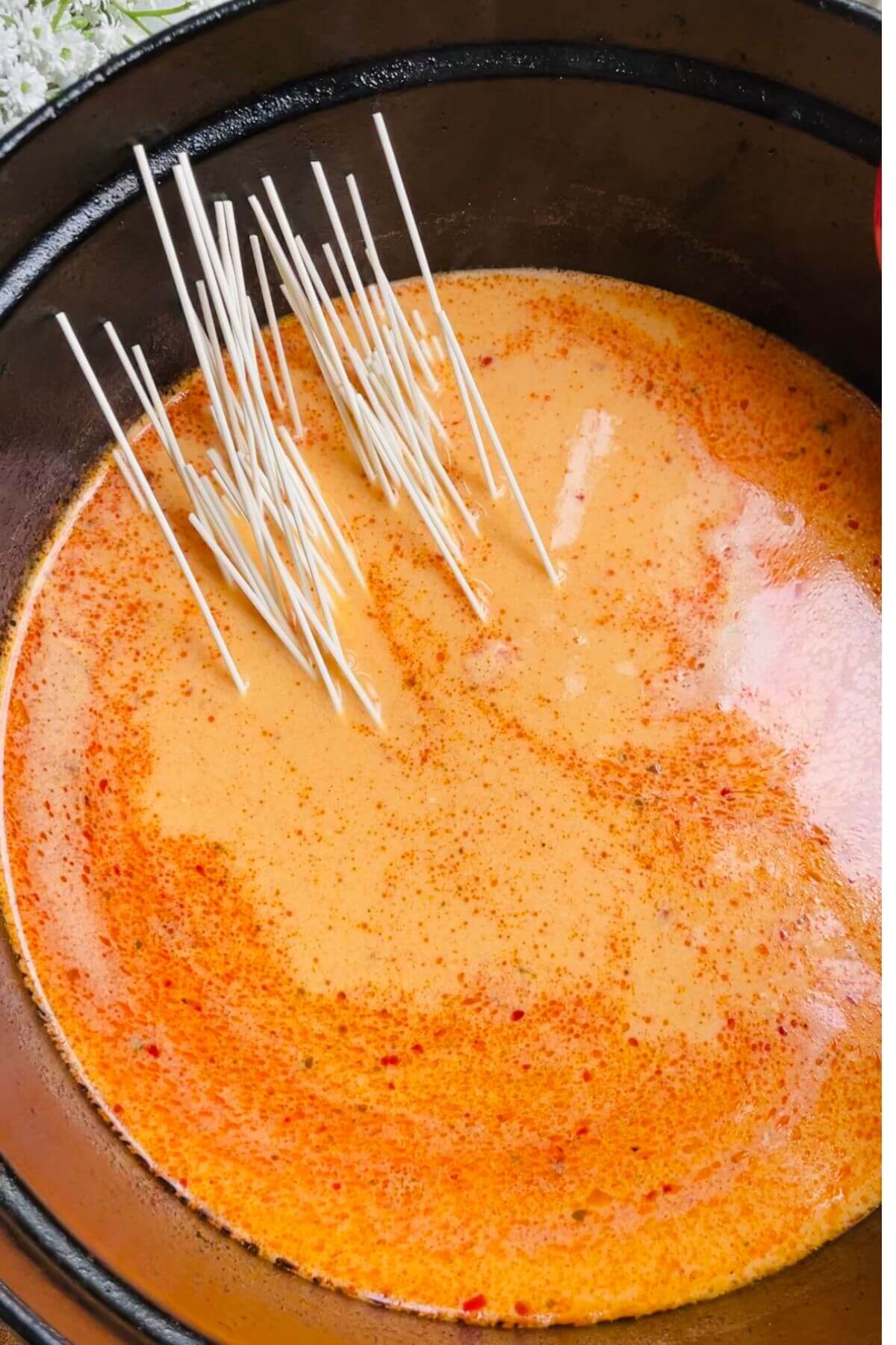 Noodles added to broth in pot.