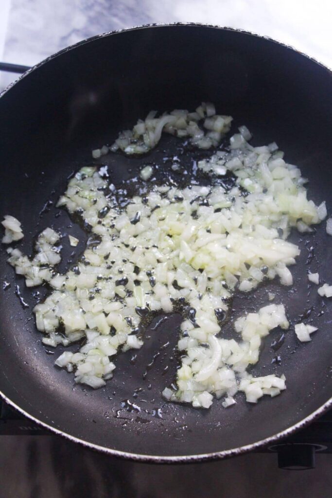 Diced onion in a small black pan.
