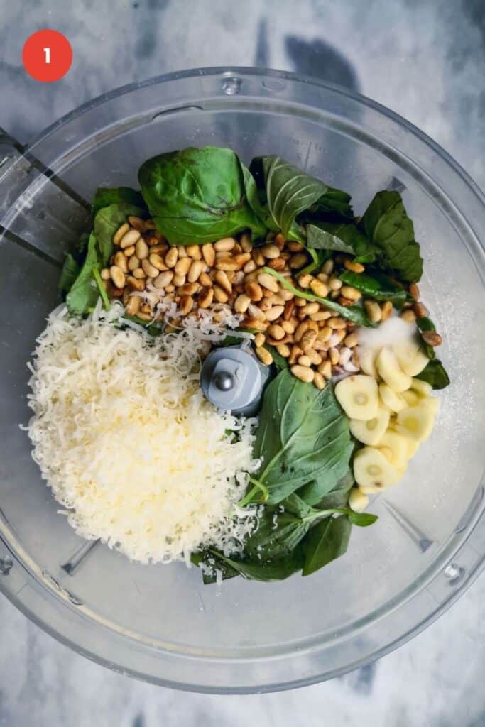 Ingredients for basil pesto in the bowl of a food processor.