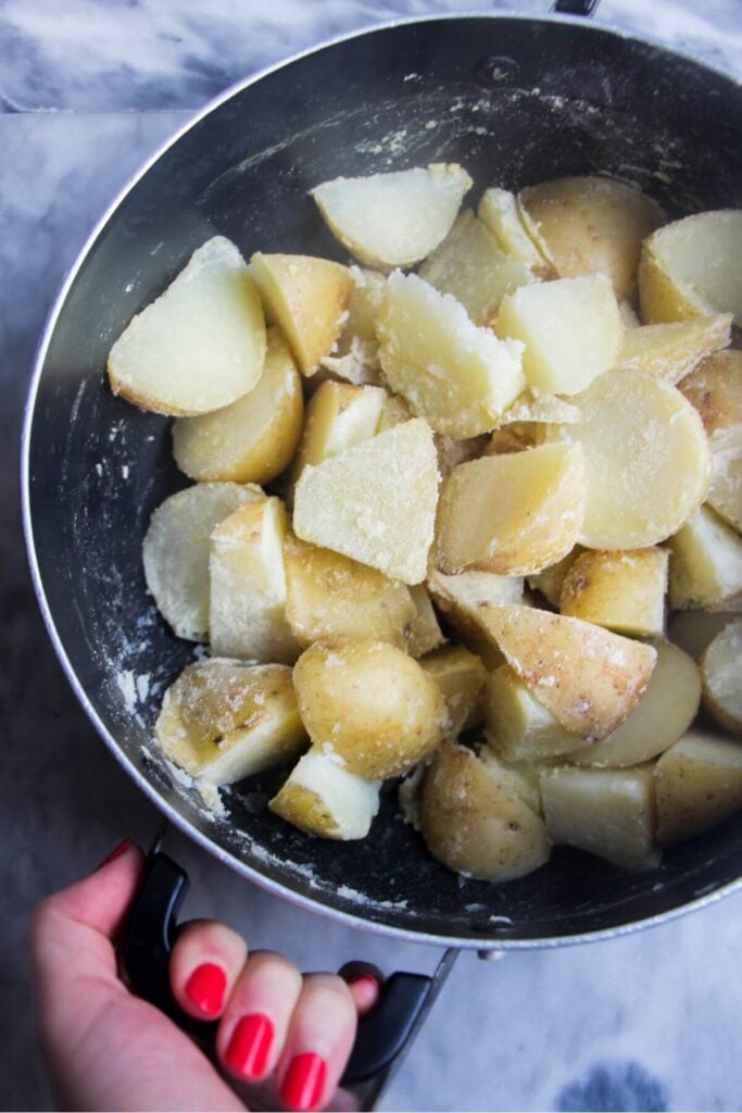 Hand shaking pot with potatoes and polenta.