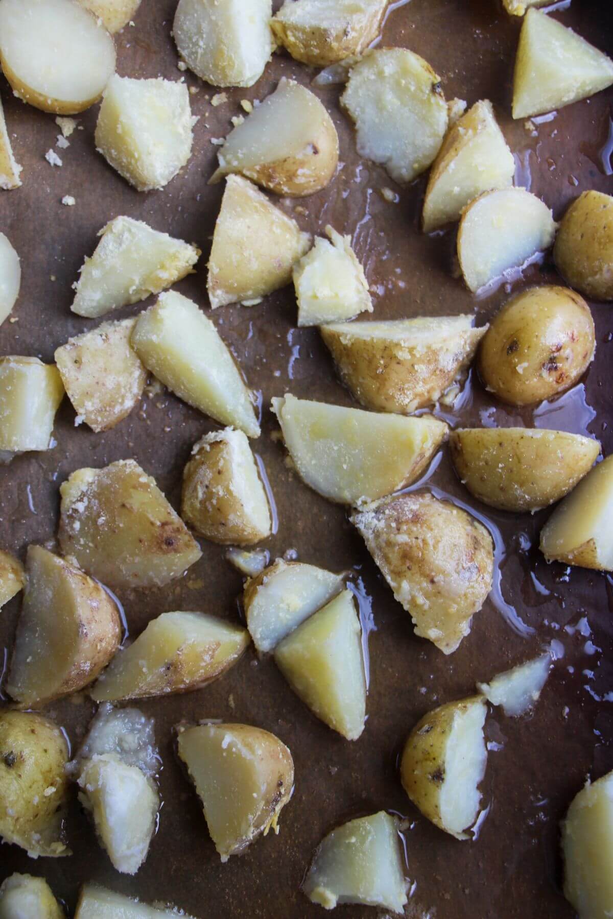 Par-boiled potatoes laid out on a baking paper lined oven tray.