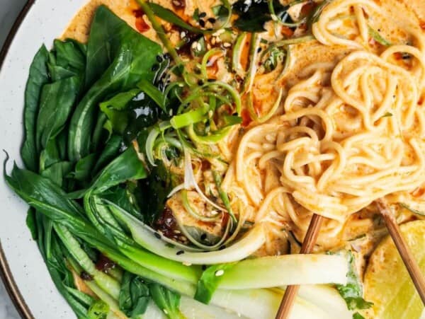 Quick spicy coconut noodles in a bowl on a grey marble background with chopsticks in the bowl.