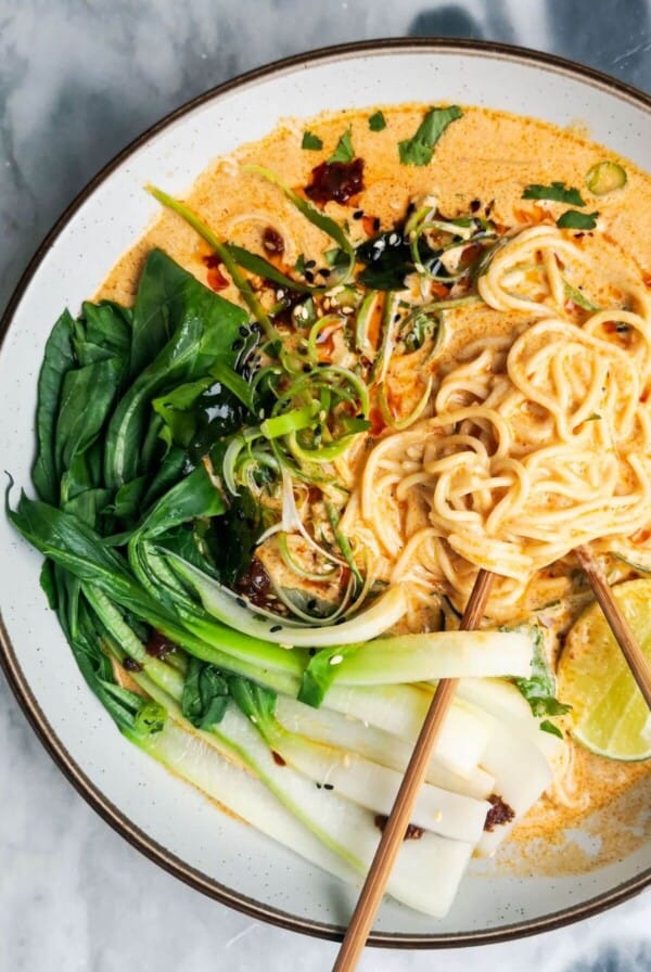 Quick spicy coconut noodles in a bowl on a grey marble background with chopsticks in the bowl.