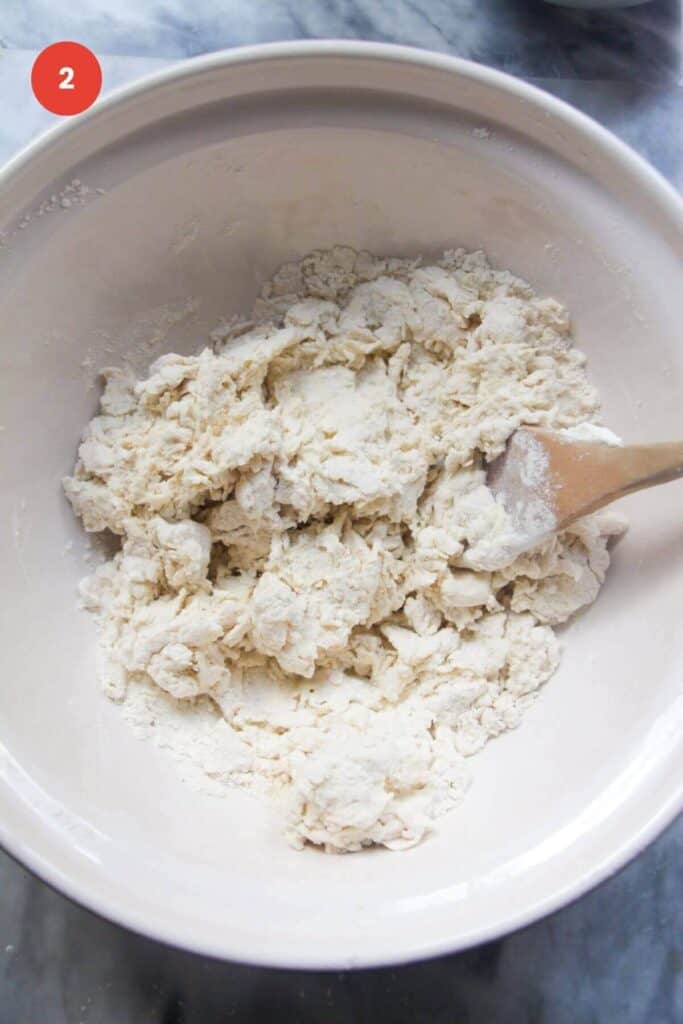 Shaggy flour and yogurt dough in a bowl with spatula.