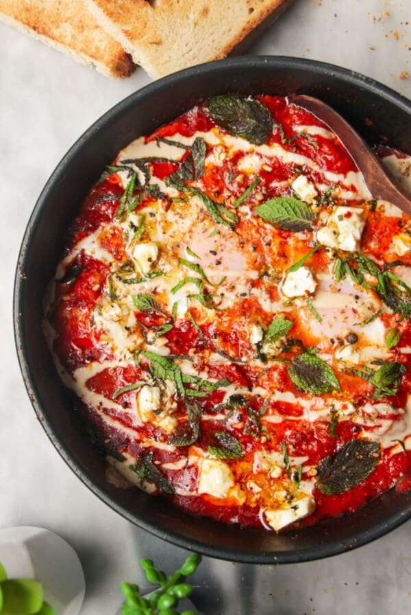 Shakshuka in a small black pan with toast on the side.