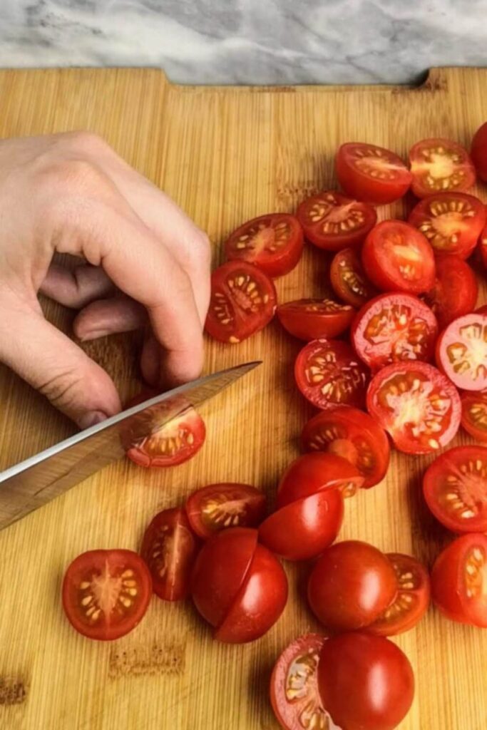 Slicing cherry tomatoes on a wooden board.