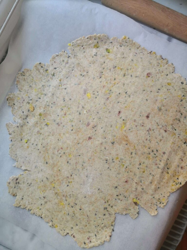 Sourdough discard crackers rolled out on white baking paper.
