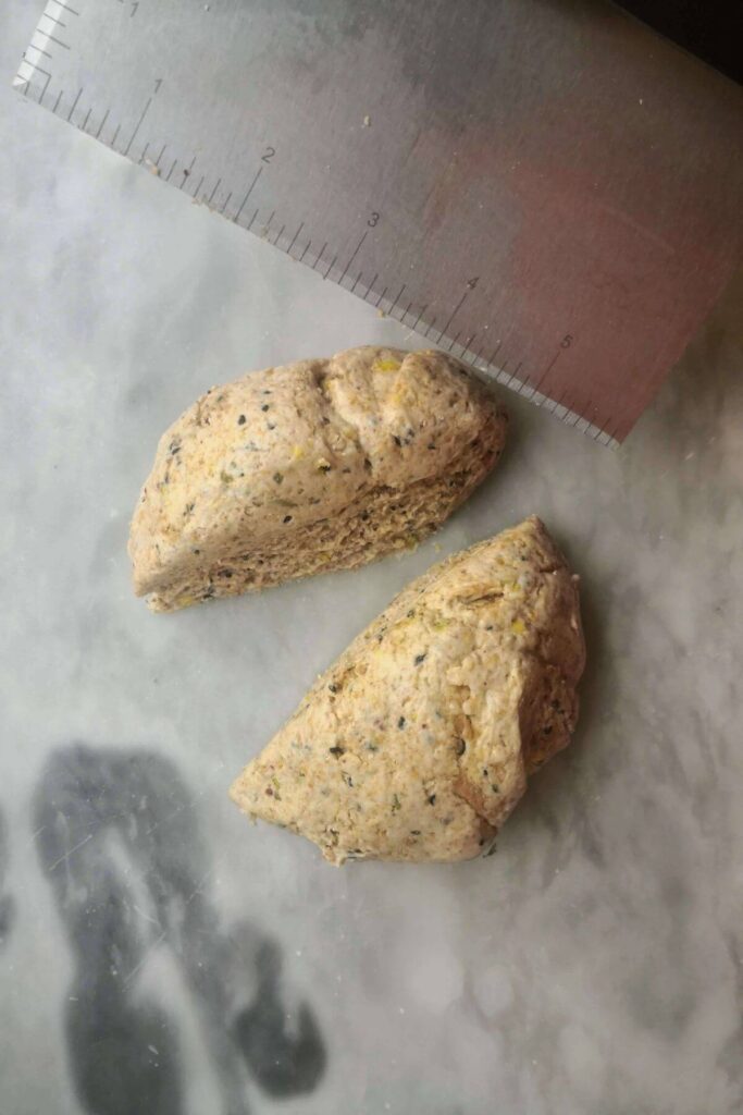Sourdough discard cracker dough being cut in half with metal dough scraper.