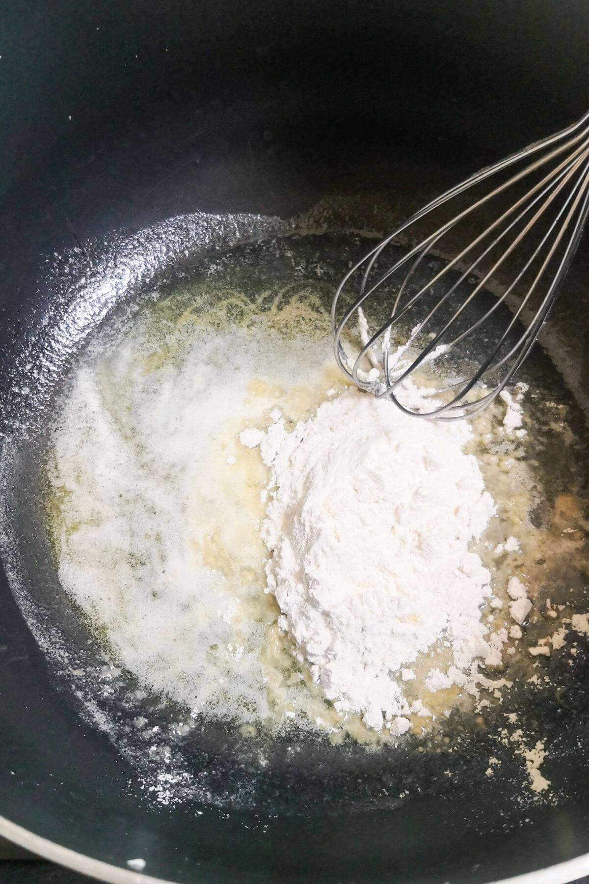 Flour added to melted butter in a large black pot.