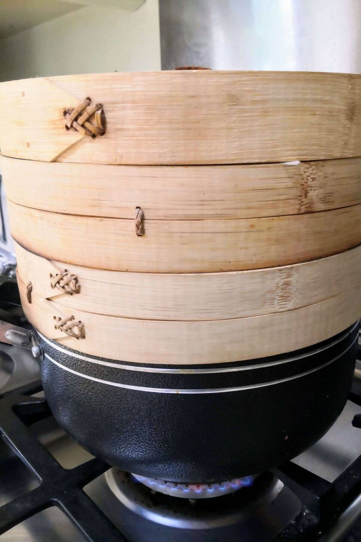 Bamboo steamer sitting on top of a large black pot.