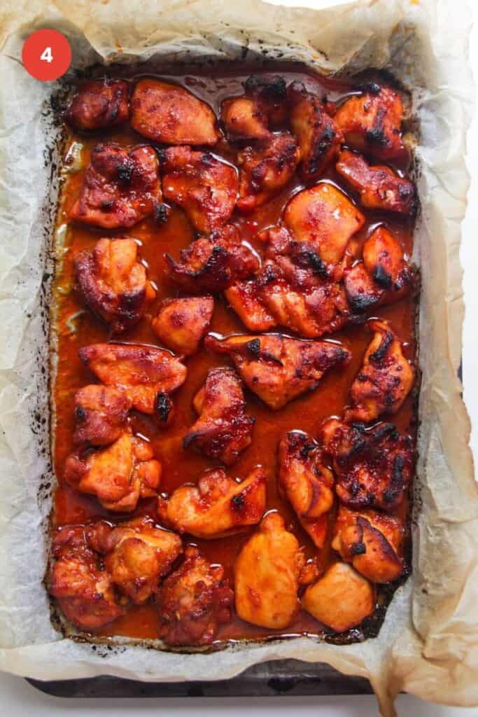 Cooked, charred gochujang chicken on oven tray.