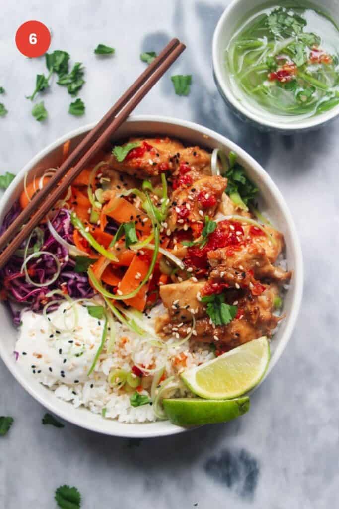 Chicken poke bowl with chopsticks and lime wedge on the side.