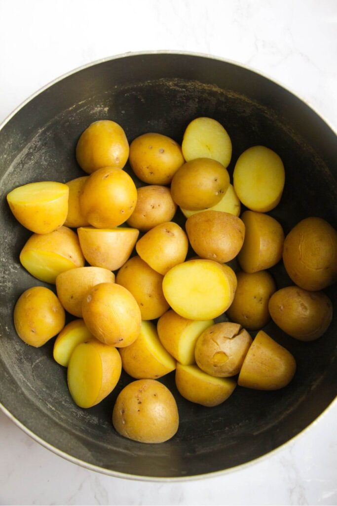 Cooked baby potatoes in a large black pot.