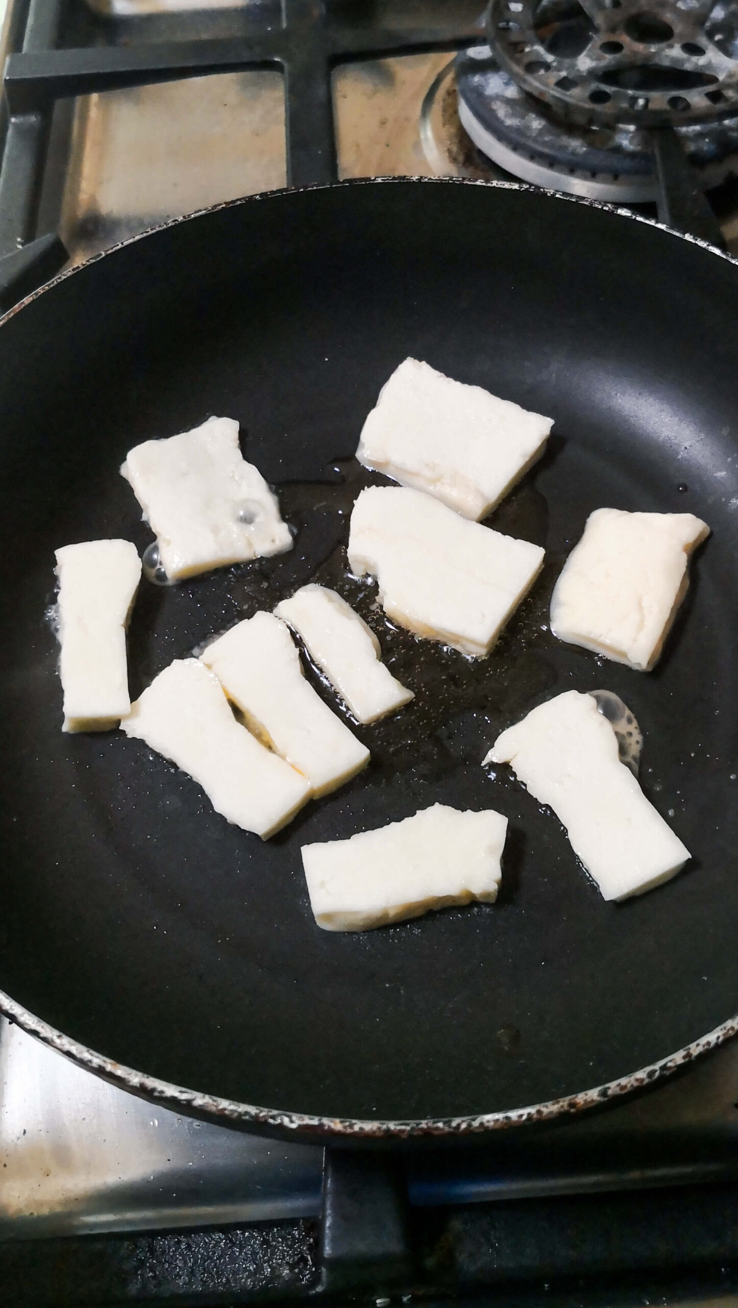 Cooking halloumi in a small black pan.