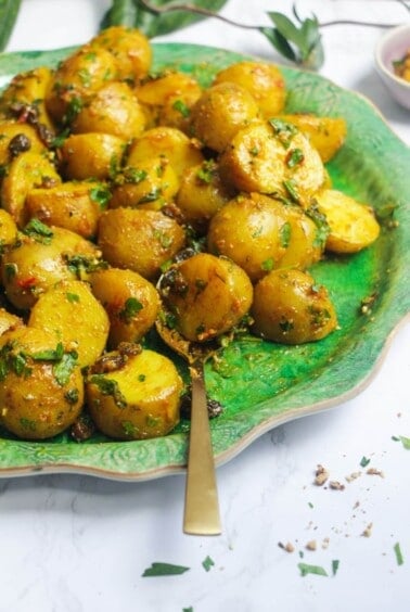 Close up of coronation potato salad on a large green platter with a gold serving spoon.