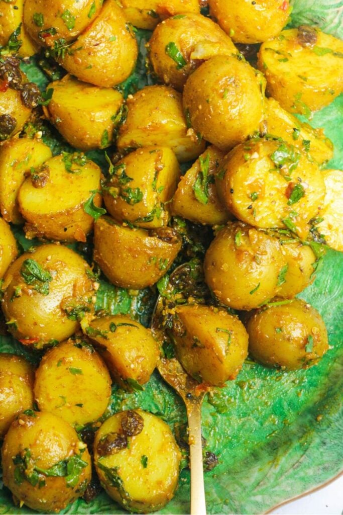 Close up of coronation potato salad on a large green platter with a gold serving spoon.
