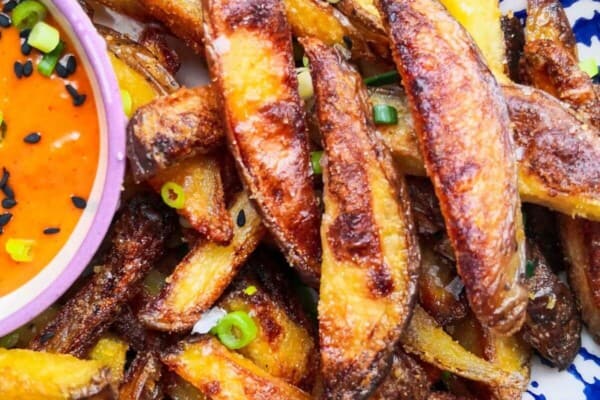 Homemade oven chips with spicy gochujang aioli in a white and blue striped bowl.