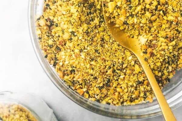 Dukkah in a small glass bowl with a jar on the side.