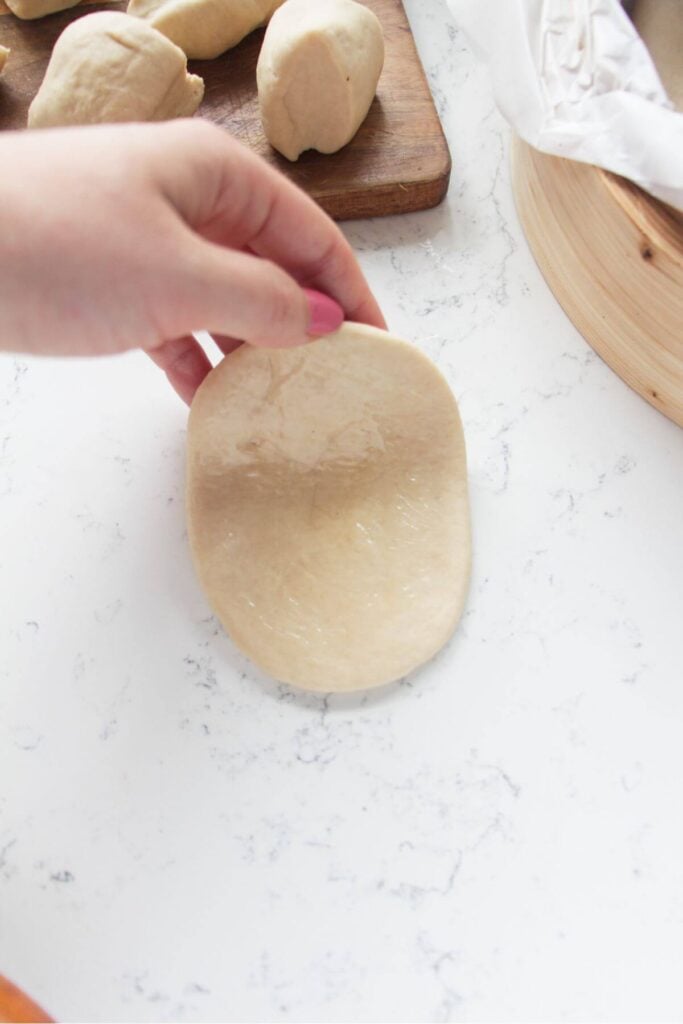 Hand folding bao bun in half.