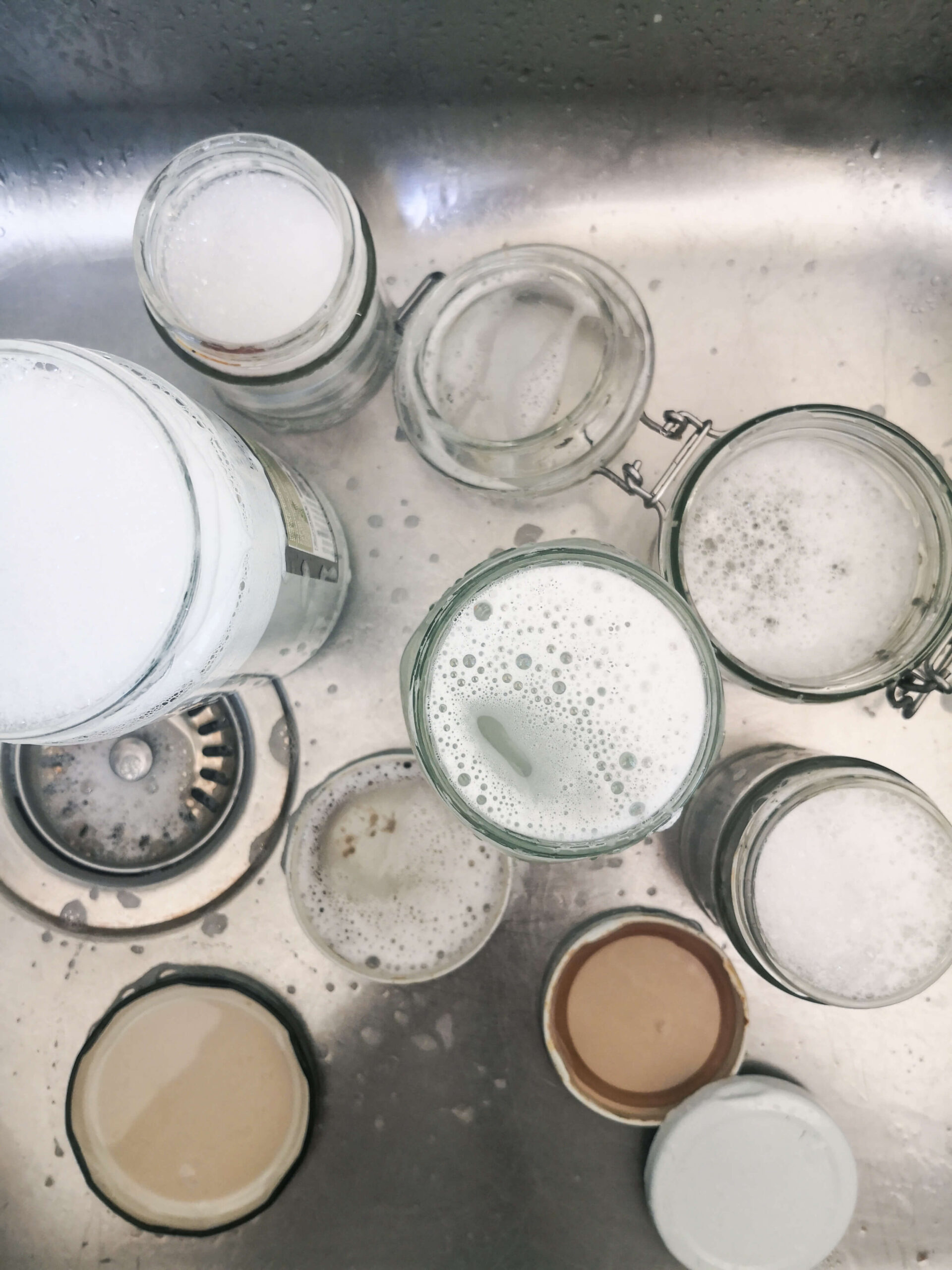 Glass jars washed in soapy water in the sink.