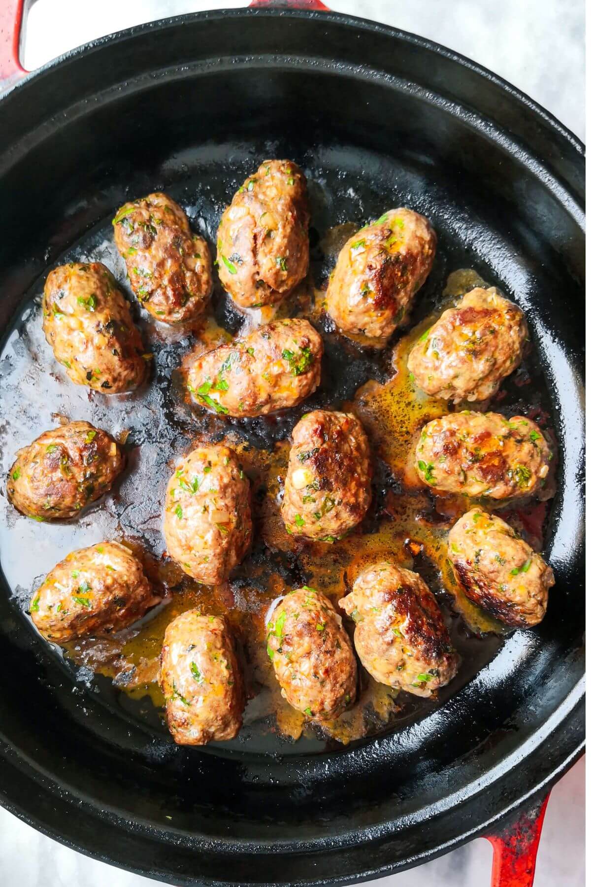 Cooked and golden lamb kofta sitting in a black skillet.