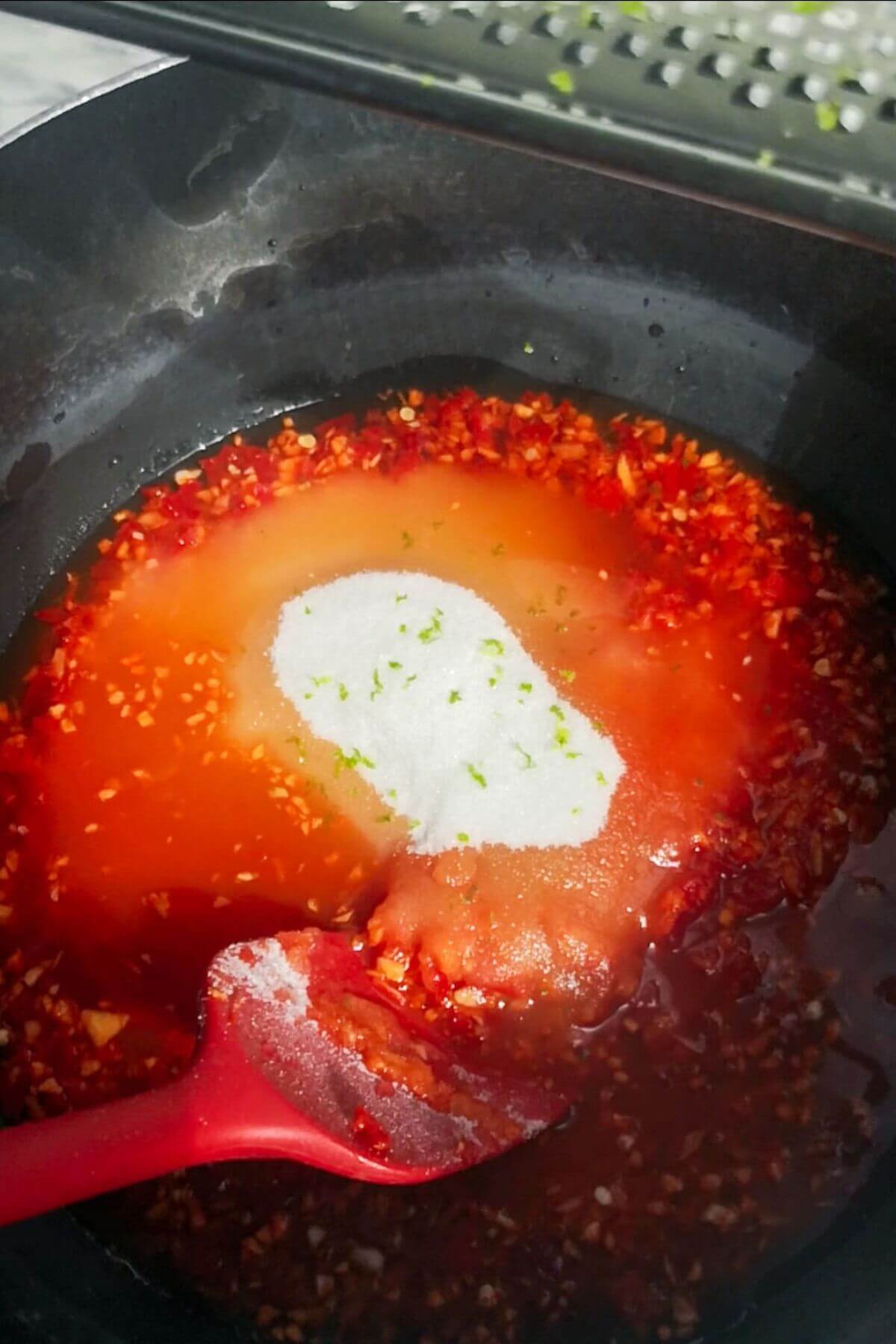 All other chilli jam ingredients being added to the chilli, ginger, garlic paste in a large black pot.