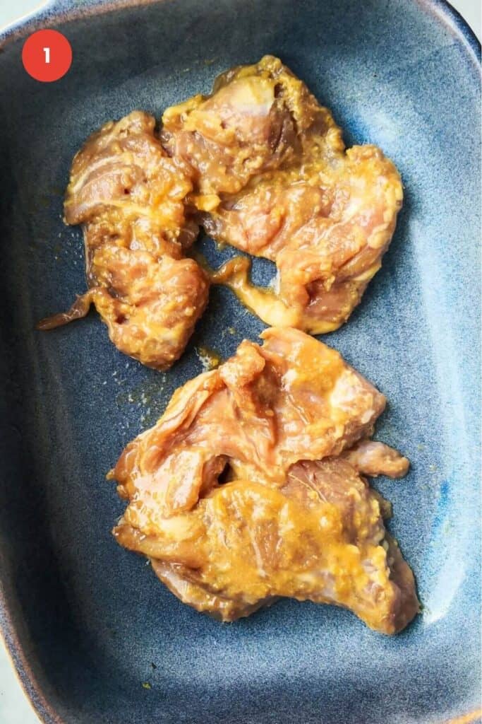 Marinated chicken thighs in a baking dish.