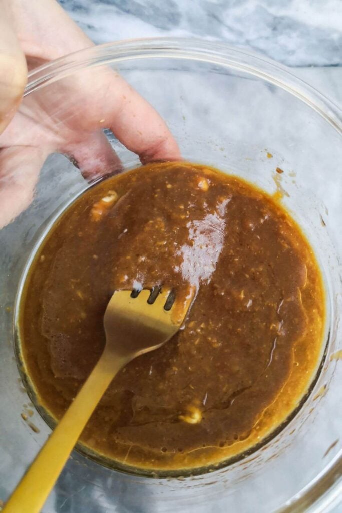 Miso marinade mixed together in a small glass bowl with a gold fork in it.