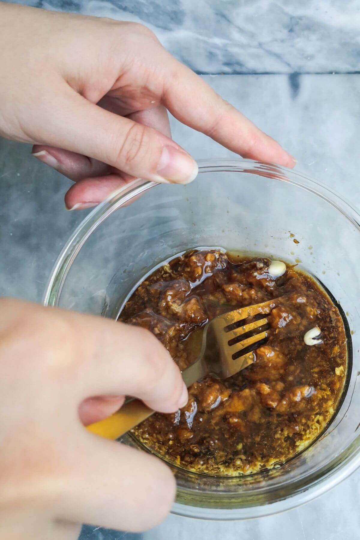 Mixing the miso marinade in a small glass bowl with a gold fork.