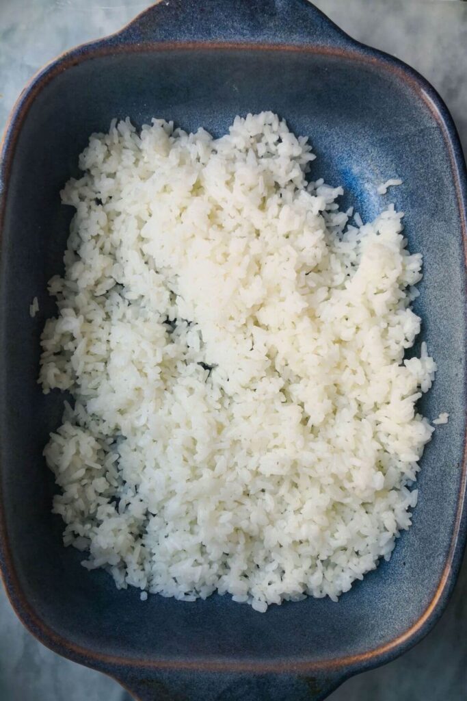 Sushi rice in a blue dish on a grey marble background.