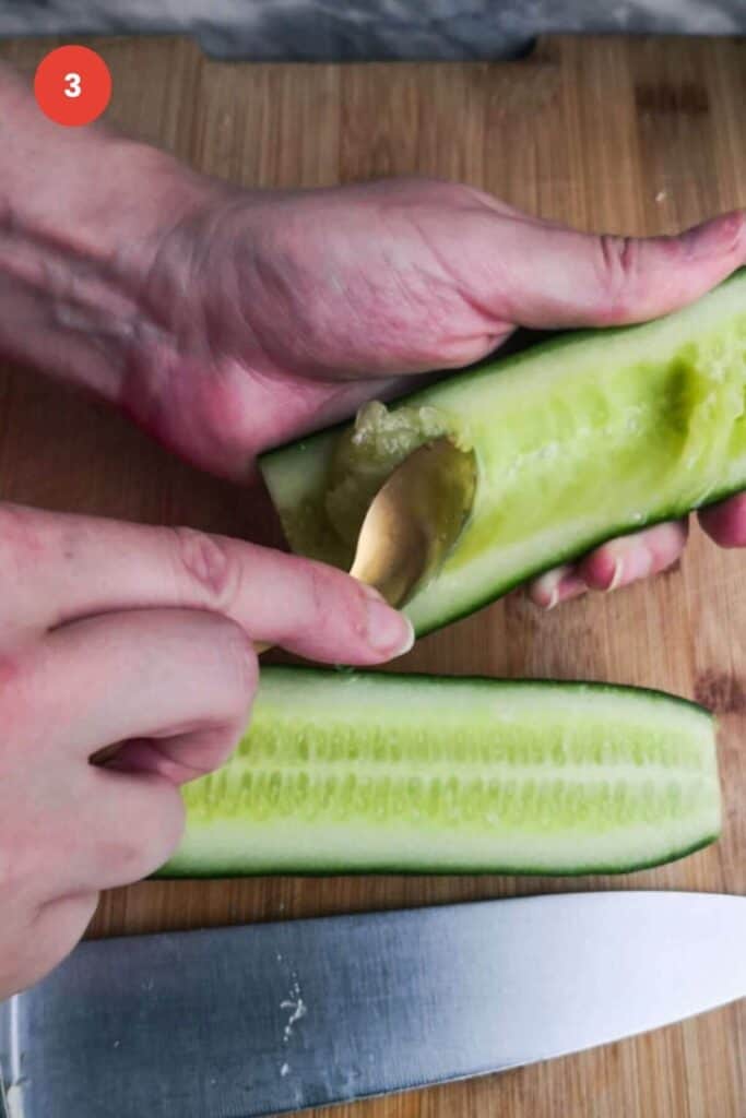 Spoon scooping out cucumber seeds.