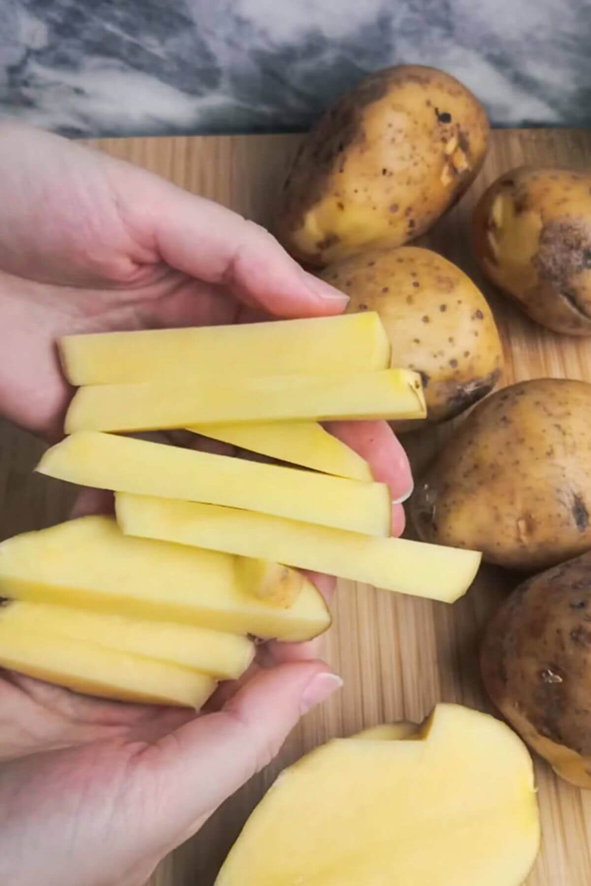 Hands holding up cut potato chips.