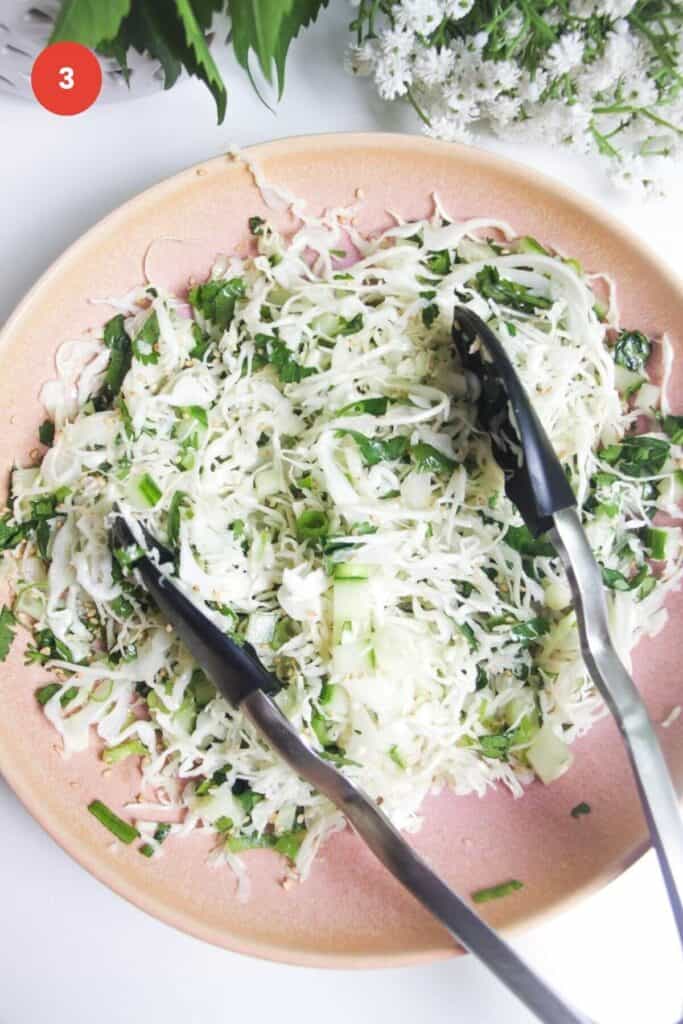 Sesame slaw in bowl with tongs.