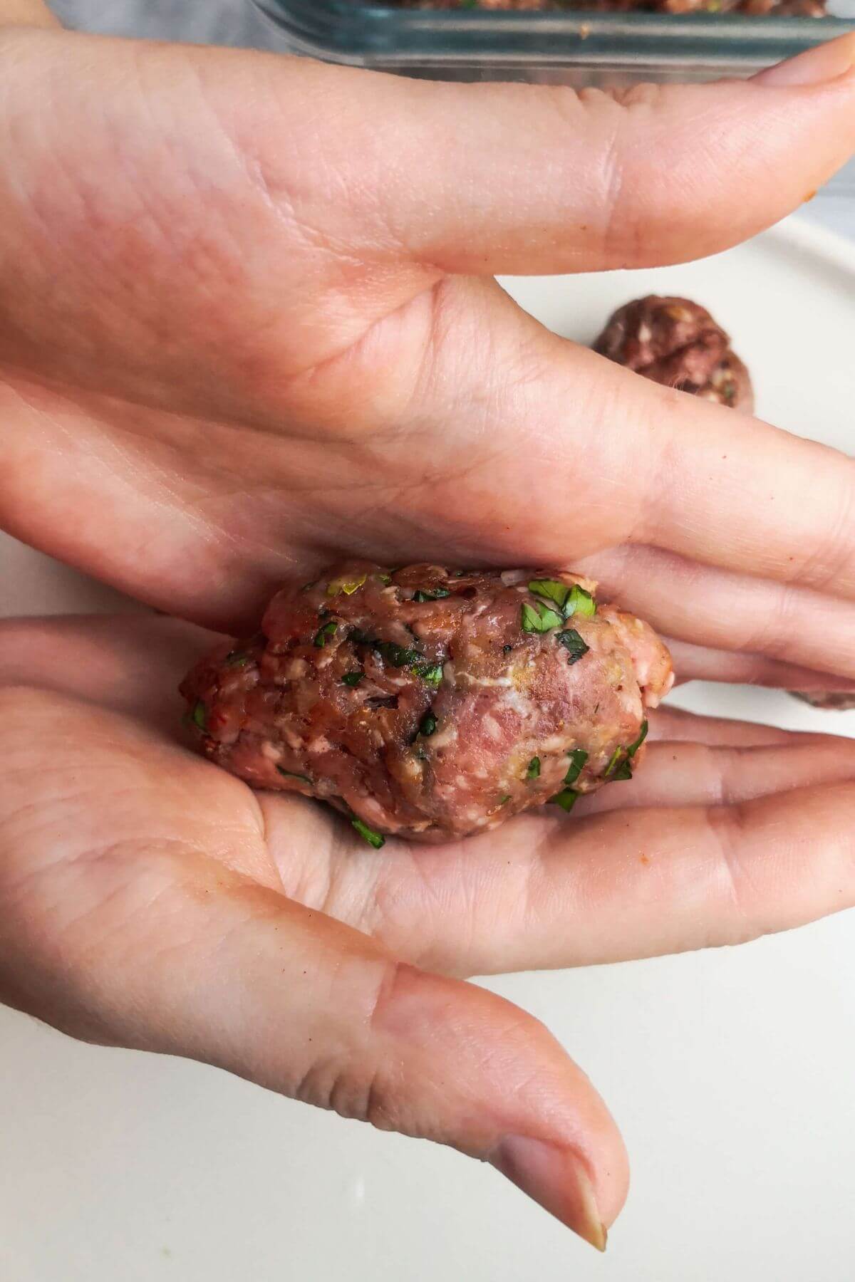 Lamb kofta shaped into an oval in two hands.