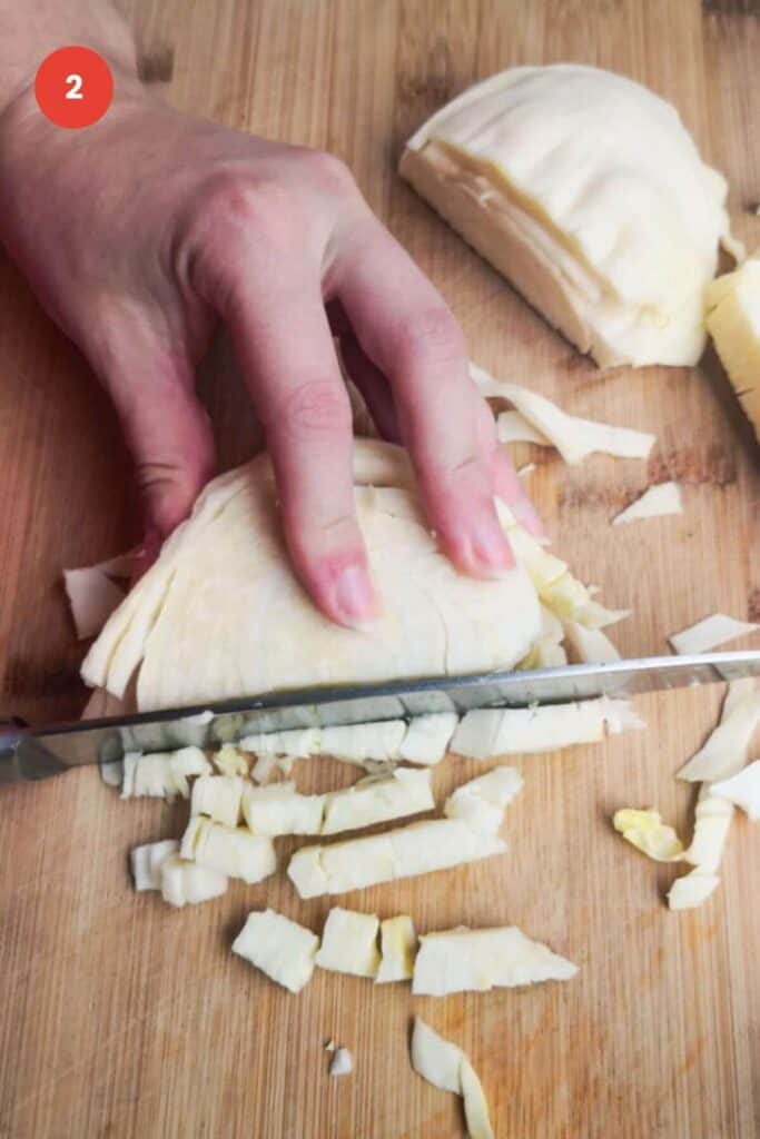 Slicing white cabbage on a wooden board.